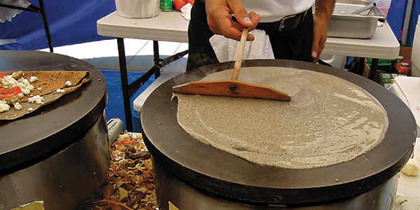 At La Crêpe à Moi’s farmers’ market tent, Dj Dahmani uses a rateau (traditional French wooden crêpe tool) to carefully spread the buckwheat batter onto a hot griddle.