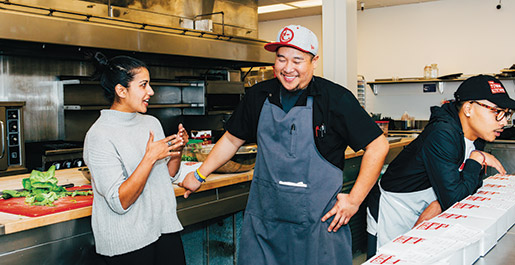 Kitchen founders Sabrina Mutukisna and Jefferson Sevilla find time for a chat as Rashawn Moore (at right) helps to organize the lunchtime delivery. 